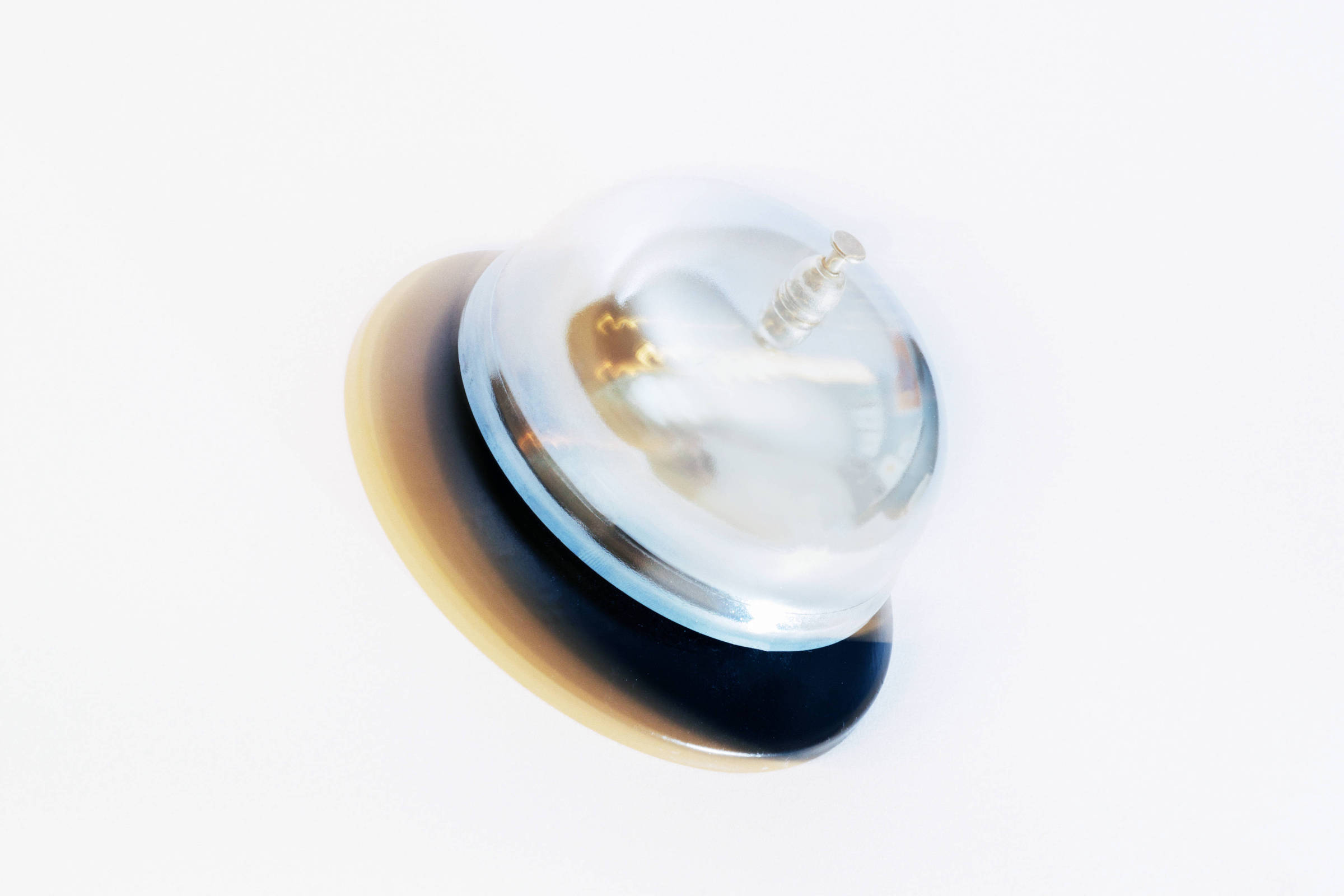 A imagem mostra um objeto transparente em forma de cúpula, com uma base arredondada de cor preta e uma parte inferior em tom claro. O objeto parece ser um tipo de botão ou interruptor, com um pequeno parafuso visível na parte superior.