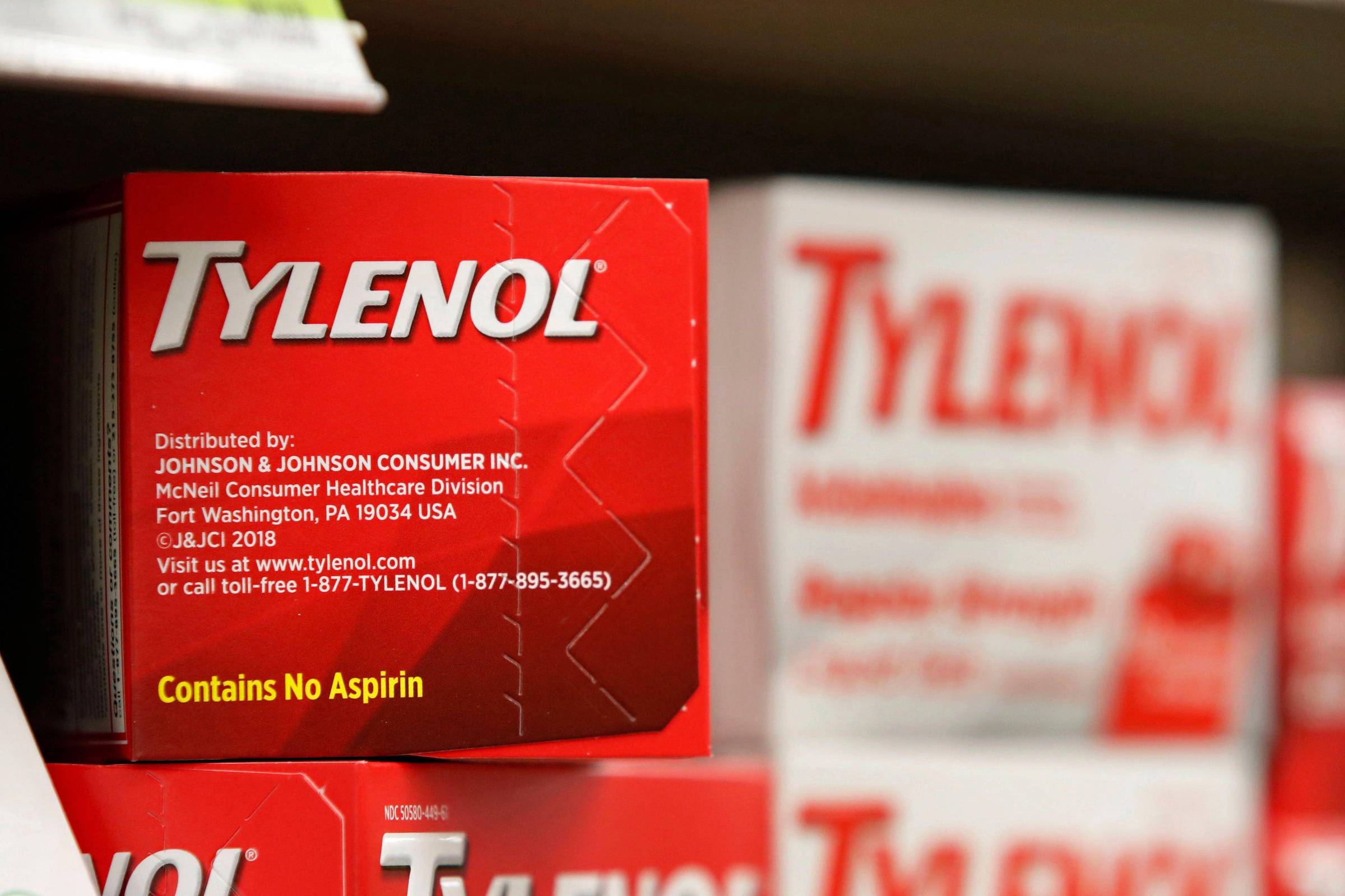 A imagem mostra uma caixa de Tylenol, um medicamento analgésico, em uma prateleira de farmácia. A caixa é predominantemente vermelha com o nome