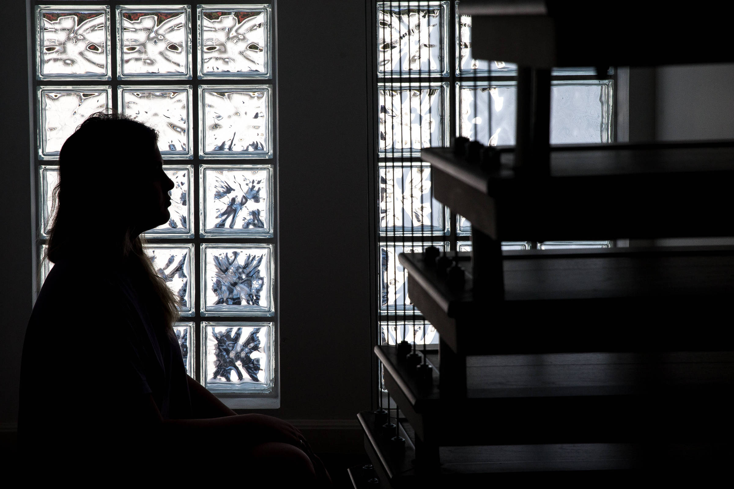 Fotografia mostra a silhueta de uma mulher sentada, contra a luz