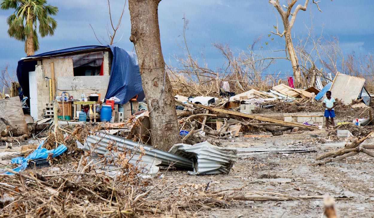 Criança fica do lado de fora de sua casa, que foi devastada por Melissa.