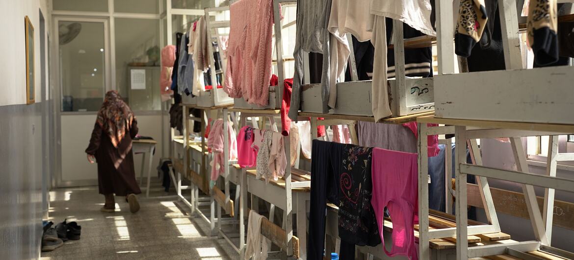 Uma mulher com um hijab caminha pela sala de aula de uma escola em Beirute, que foi convertida em um abrigo para famílias deslocadas.